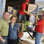 Portrait of couple and workers unloading truck